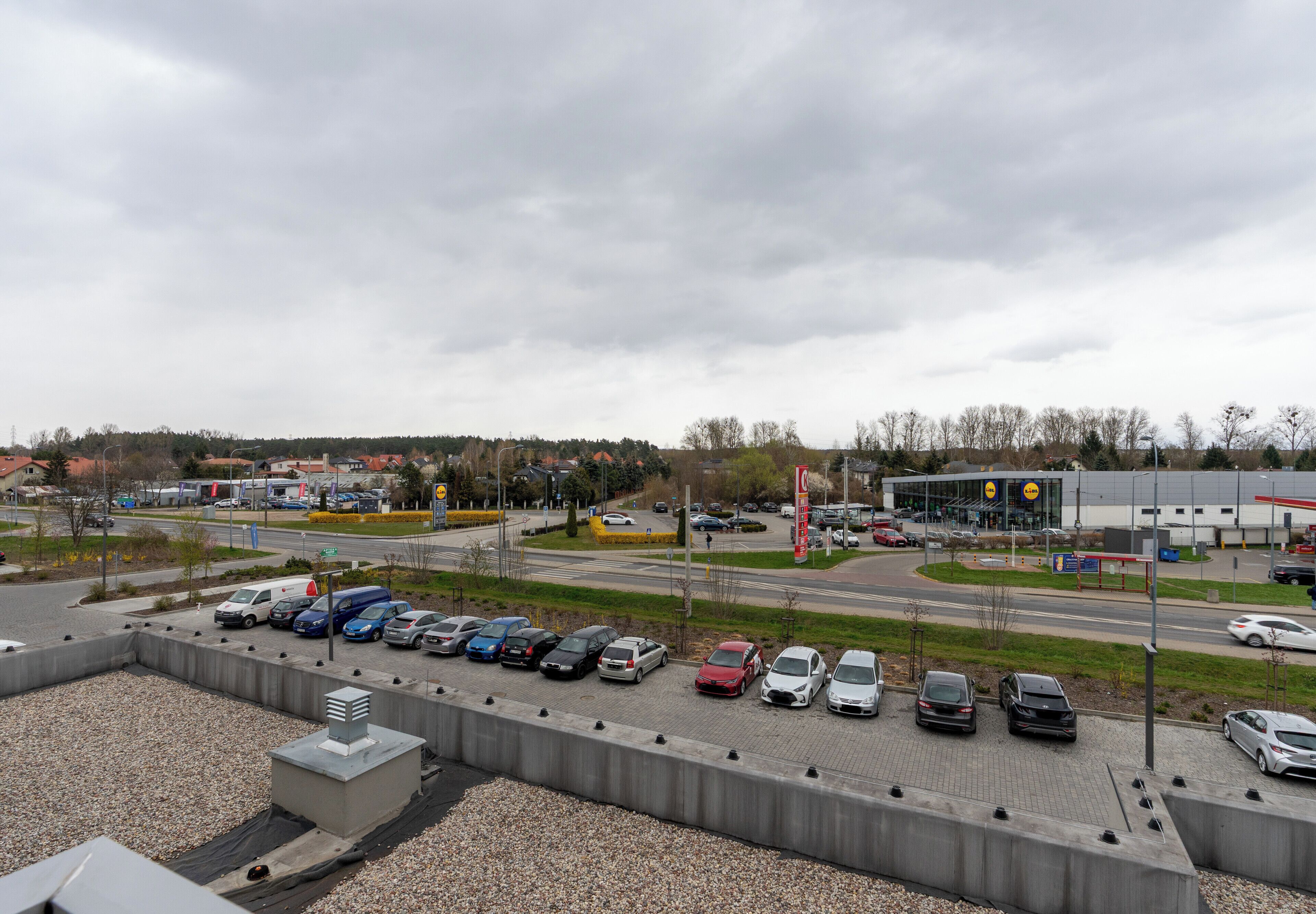A parking lot with multiple cars and a large building in the background.