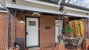 A brick house with a white door, a patio with wicker chairs and a table, and a decorative flower wall. - Spacious 5 Beds 4 Bath Midtown Home - Near Zoo and Liberty Bowl (Memphis)