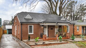 A brick house with a covered porch, a small garden, and a garage. - Spacious 5 Beds 4 Bath Midtown Home - Near Zoo and Liberty Bowl (Memphis)