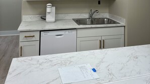 A kitchen with white cabinets, a stainless steel sink, and a white dishwasher.