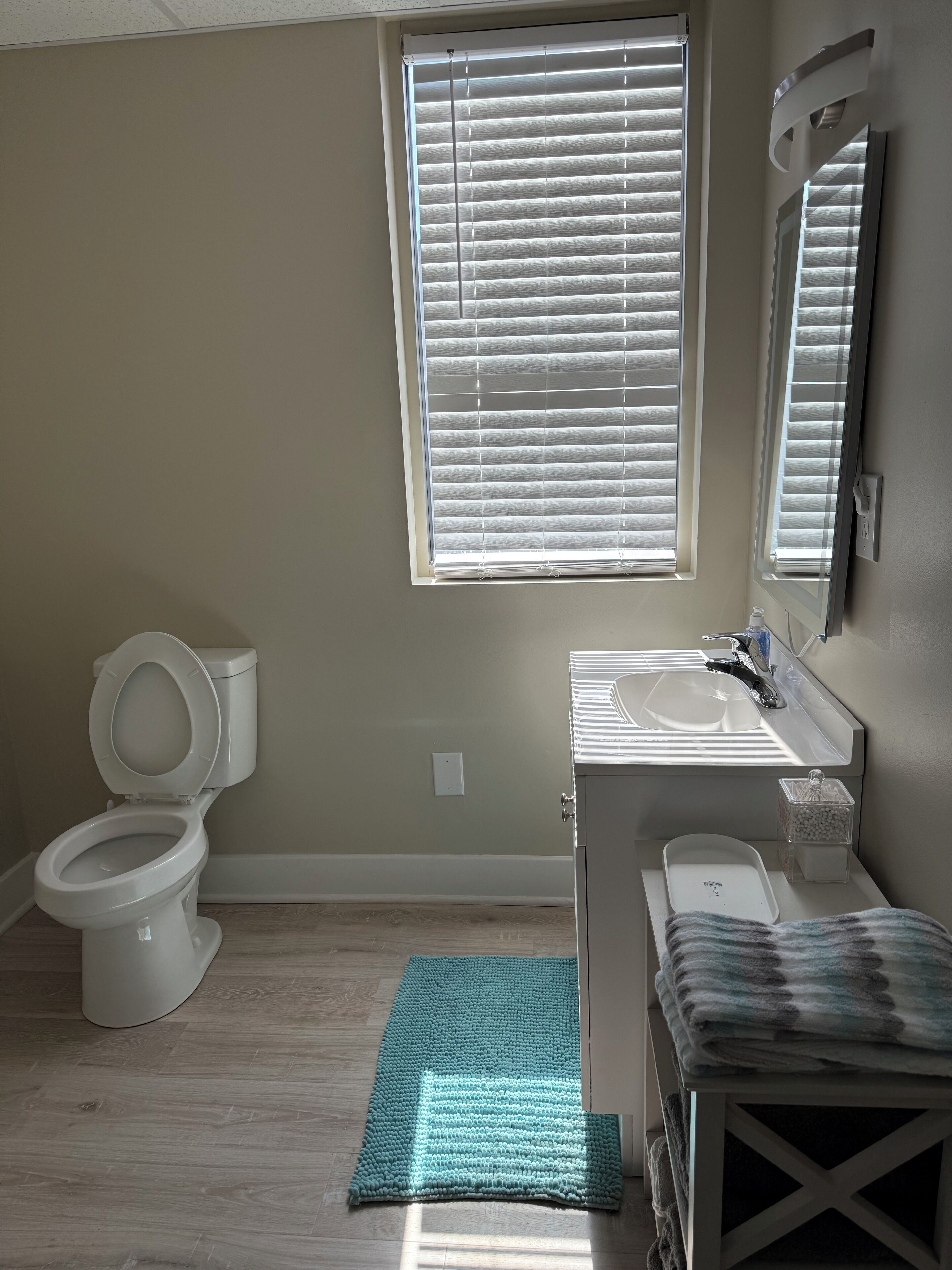 Een badkamer met toilet, wastafel en raam met zonwering.
