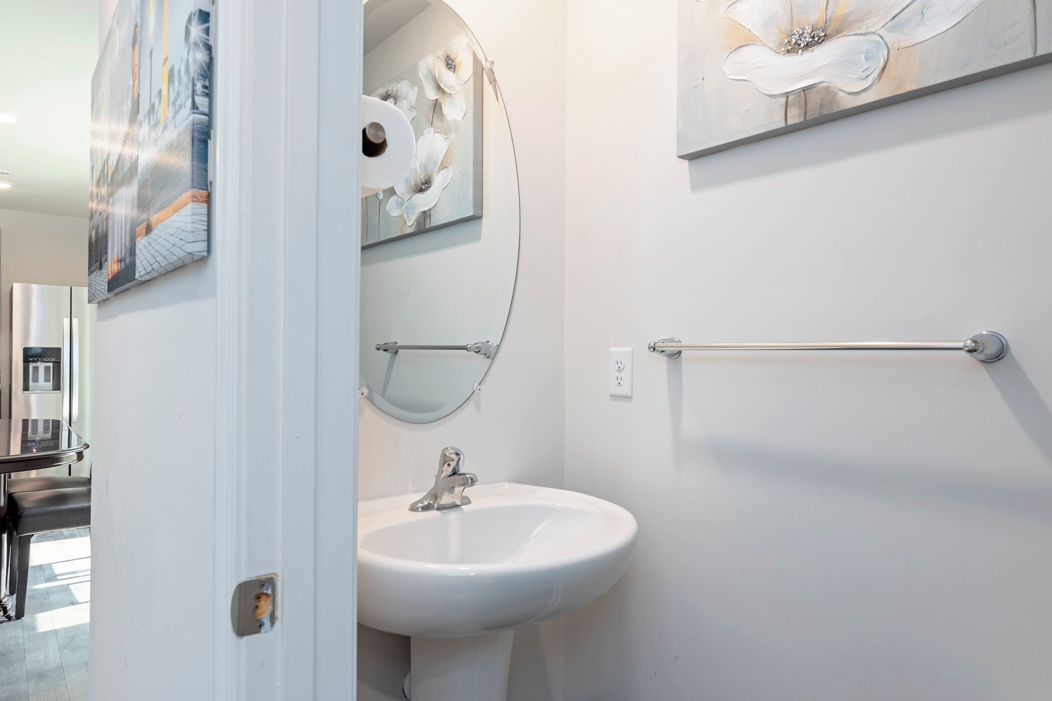 Un baño con un lavamanos blanco, un espejo y dos toalleros de pared.