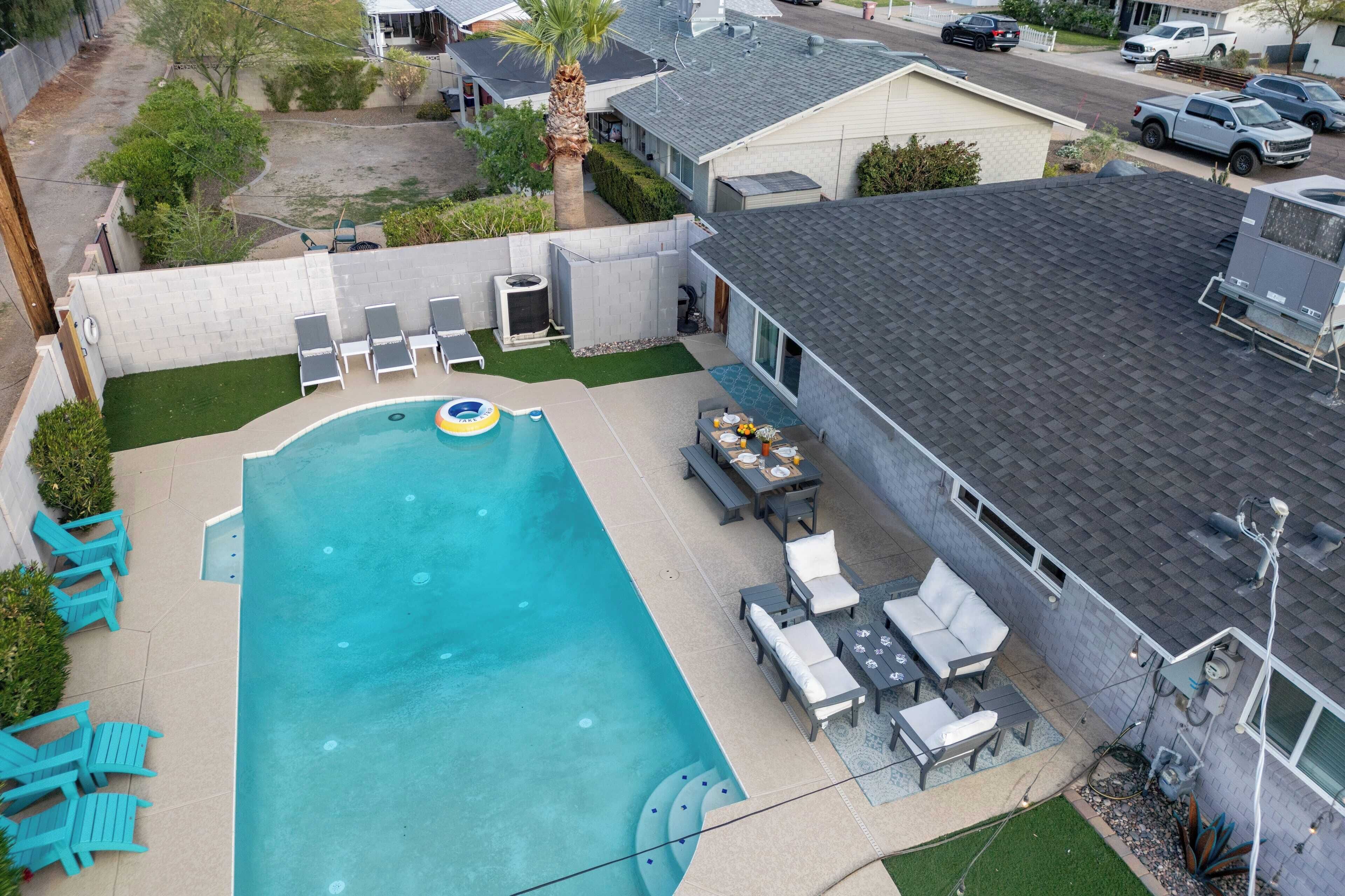 Un jardin à l’arrière d’une maison, avec une piscine, du mobilier de jardin et un petit coin repas.