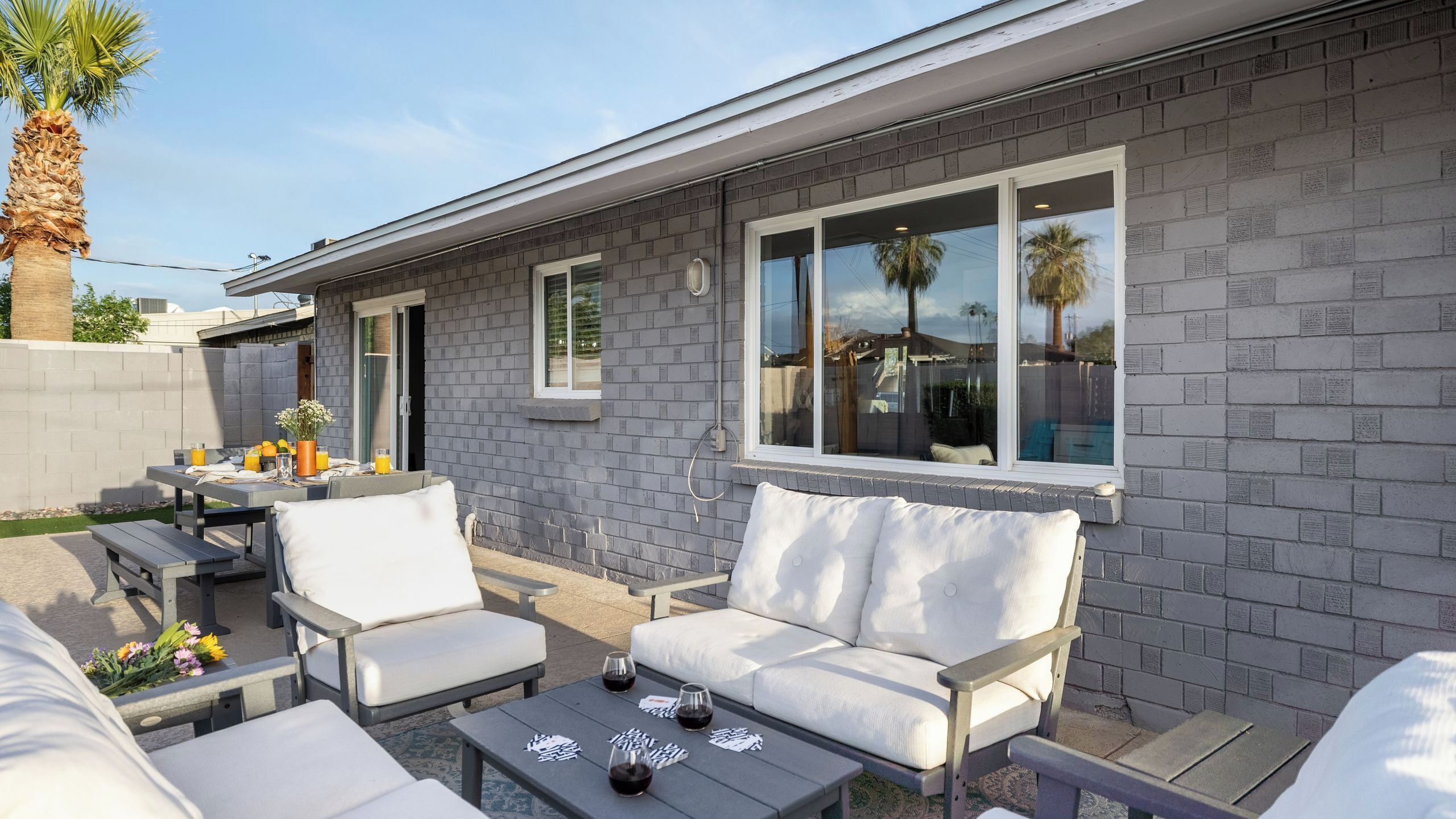 A patio with outdoor furniture, a table with drinks, and a brick wall.
