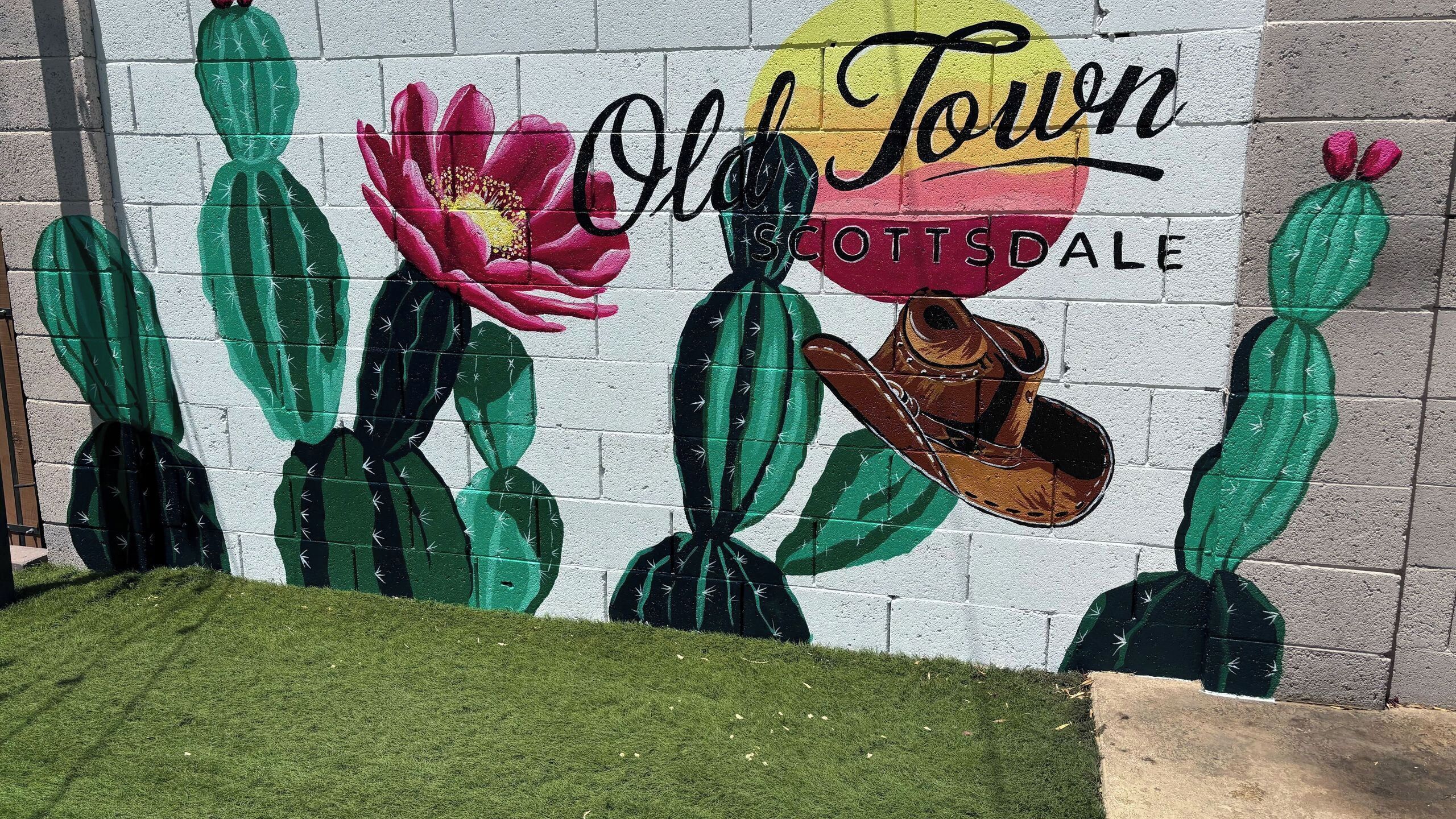 Tiiliseinään maalattu suuri seinämaalaus, jossa on kuvattuna kaktuksia, kukka ja cowboy-hattu, ja sen alla teksti: ”Old Town Scottsdale”.