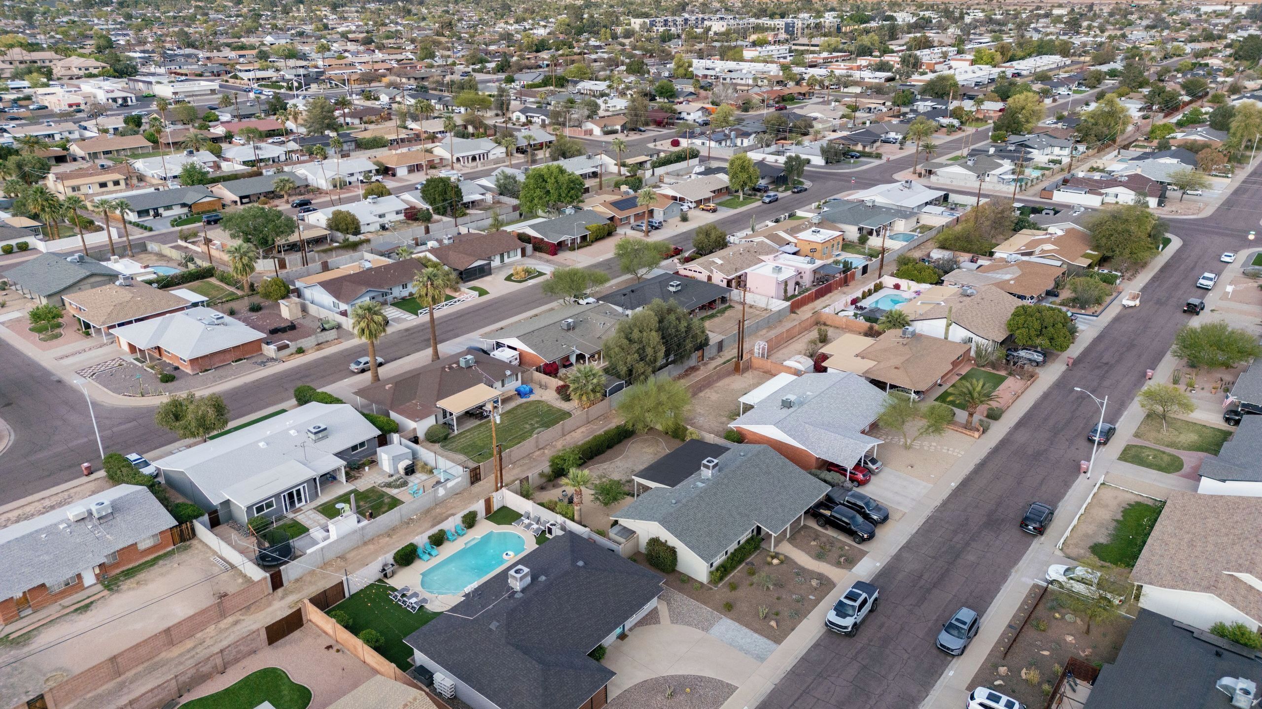 A residential area with houses, streets, and a swimming pool.