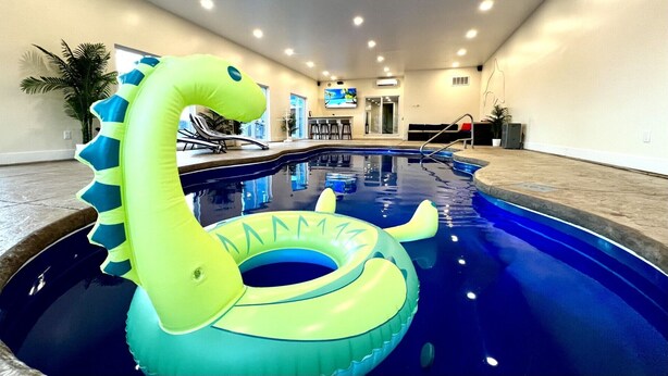 An indoor swimming pool with a green inflatable swan float, lounge chairs, and a bar area. - Private Heated Indoor Pool + No Neighbors + Ski Shawnee/Camelback (East Stroudsburg)