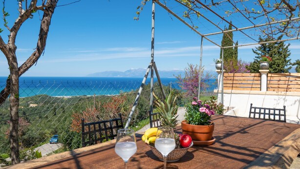 A table with two glasses of a clear liquid, a bowl of fruit, and a potted plant. - Corfu Hillside Villa – Terrace, Nature Walks, Sea Views (Agios Martinos)
