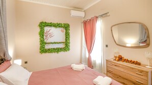 A bedroom with a bed, a dresser, a mirror, and a wall decoration. - Corfu Hillside Villa – Terrace, Nature Walks, Sea Views (Agios Martinos)