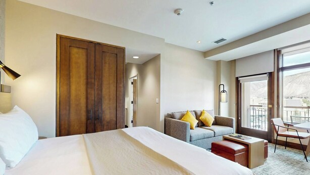 A hotel room with a large bed, a sofa, a desk, and a balcony with a view. - 1BR ski-in/out condo at Westin Riverfront with valley views. (Avon)