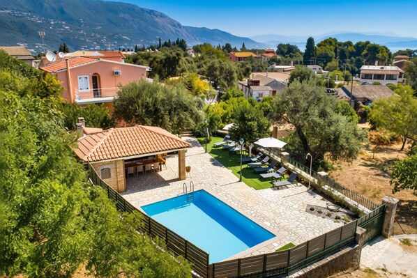 Ein Wohngebiet mit Schwimmbad, einer Terrasse mit Liegestühlen und einem Berg im Hintergrund.