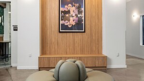 A modern lobby with a round seating area, a large wall-mounted artwork, and a ceiling light fixture. - Little Italy Inn - Limited Service Apart Hotel (San Diego)