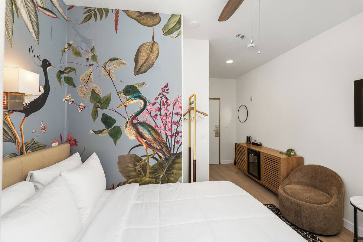 A bedroom with a bed, a nightstand, a lamp, a wooden cabinet, and a round chair.