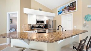 Cocina moderna con gabinetes blancos, electrodomésticos de acero inoxidable y encimera de granito.