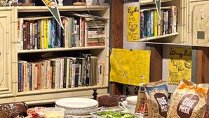 A room with a yellow table covered with food items, bookshelves, and various flags. - Charming baseball themed 2-story building with cable TV, wi-fi & stereo system. (Berkeley)