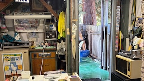 A cluttered room with various items and memorabilia, including a 'Big Fan Buffalo Bills' sign, a map, and a refrigerator with a microwave on top. - Charming baseball themed 2-story building with cable TV, wi-fi & stereo system. (Berkeley)
