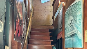 A wooden staircase with a handrail, surrounded by wooden walls and various framed pictures. - Charming baseball themed 2-story building with cable TV, wi-fi & stereo system. (Berkeley)