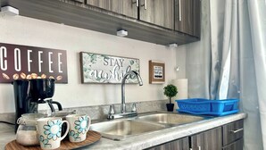 A kitchen with a coffee maker, two mugs, a blue dish rack, and motivational wall art. - Startfish #2 Apartment 9 Min to Airport FREE WI-FI (CAROLINA)