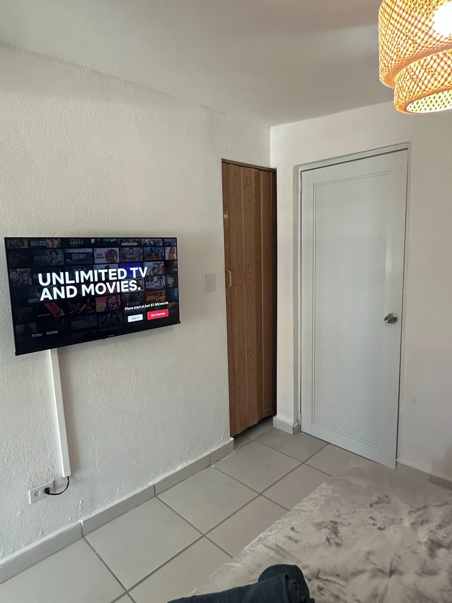 Et værelse med et ophængt fjernsyn, der viser en reklame fra en streamingtjeneste.