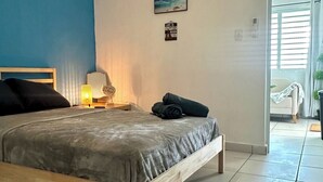 A bedroom with a bed, a bedside lamp, a wall-mounted air conditioner, a framed picture, and a door leading to another room. - Startfish #2 Apartment 9 Min to Airport FREE WI-FI (CAROLINA)