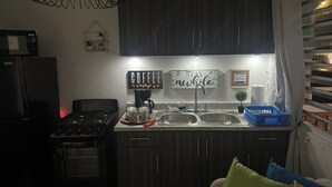 A kitchen with dark cabinets, a stove, a sink, and a coffee station. - Startfish #2 Apartment 9 Min to Airport FREE WI-FI (CAROLINA)