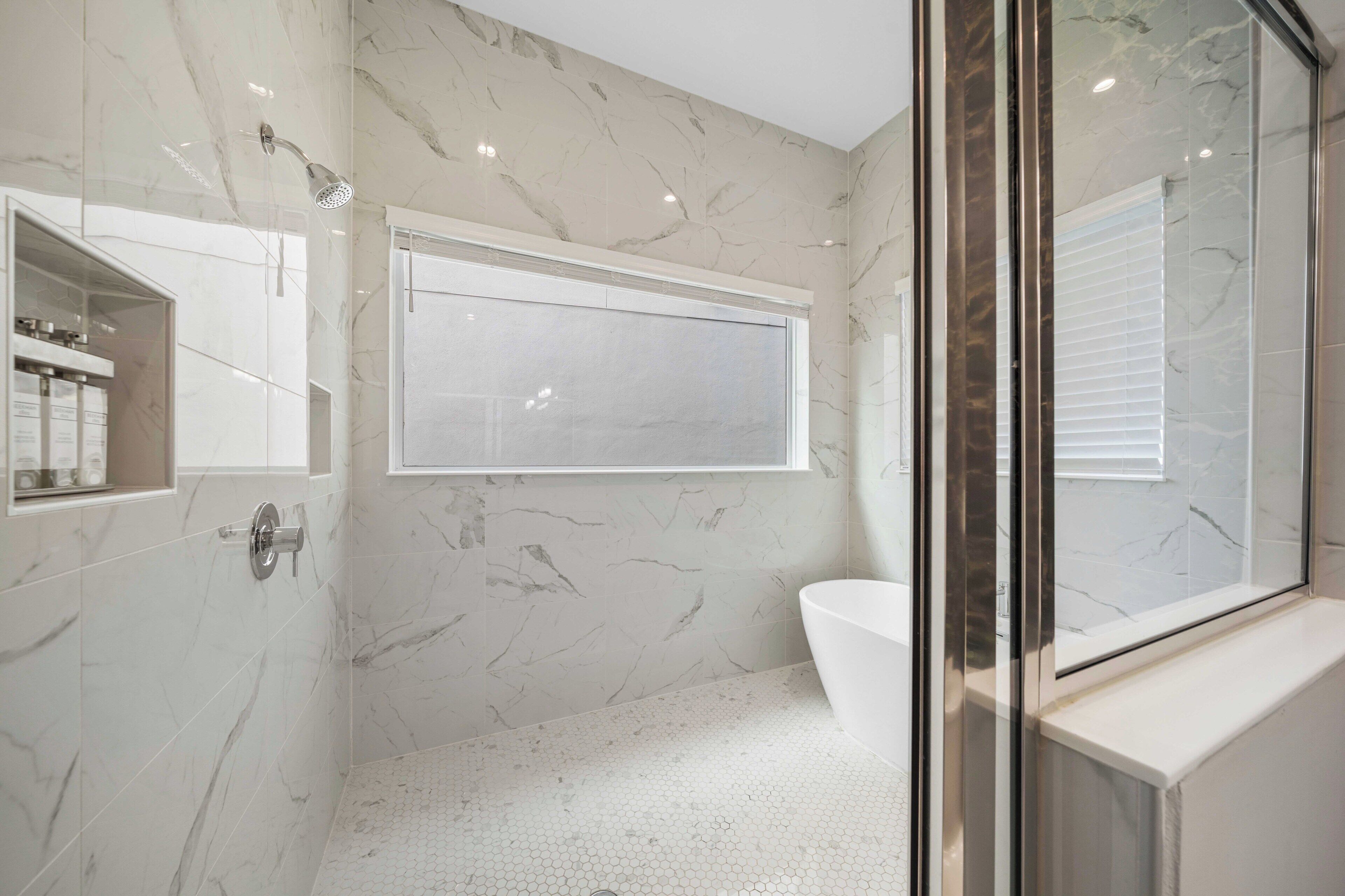 Un baño moderno con cabina de ducha de vidrio, bañera blanca y retrete.