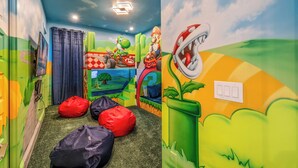 A children's playroom with colorful murals, bean bags, and a ceiling light.