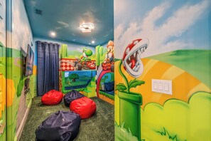 Un salón infantil con murales coloridos, pufs y una lámpara en el techo.