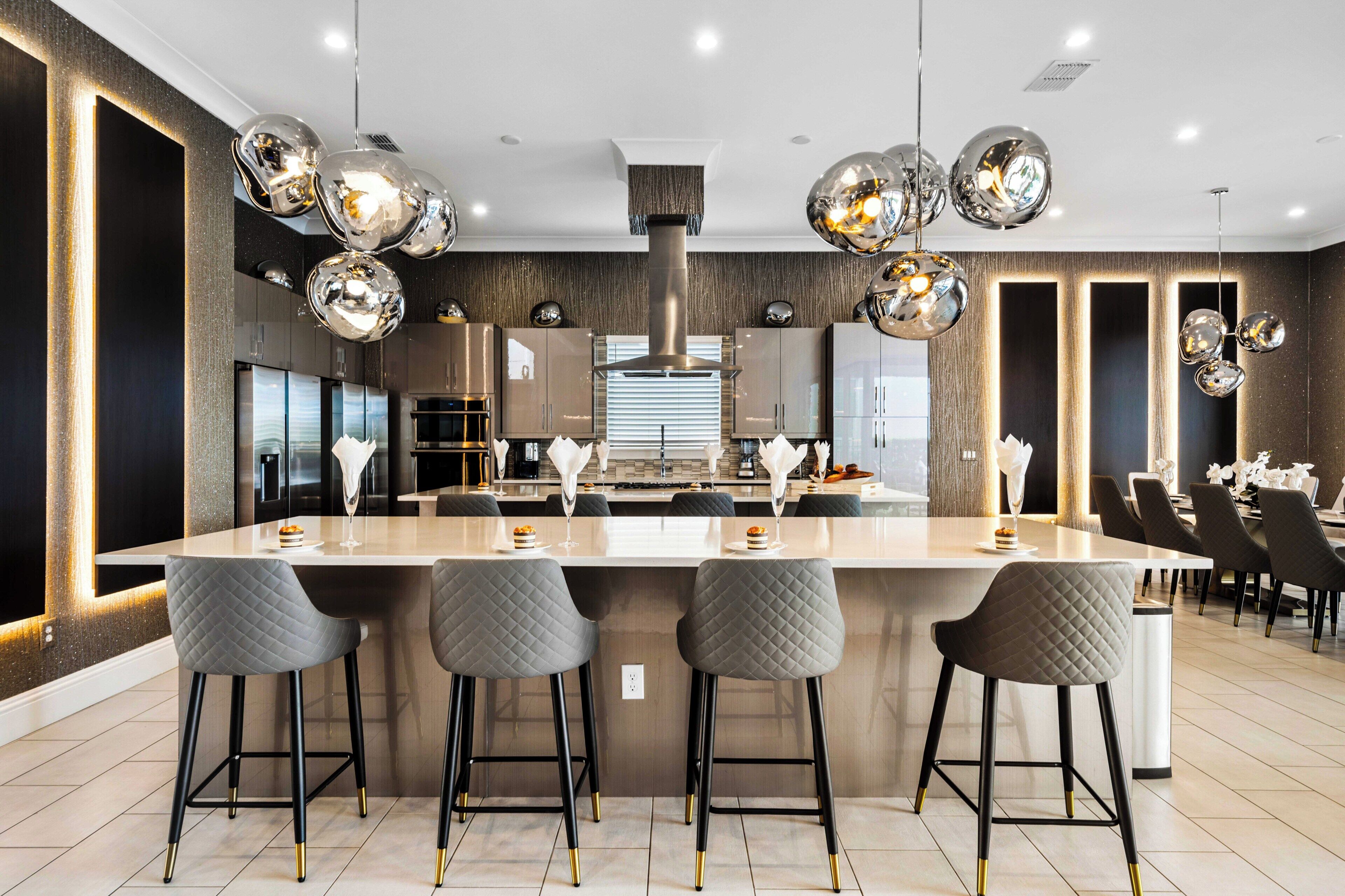 Een moderne keuken met een centraal eiland, barkrukken en hanglampen.