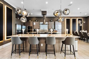 A modern kitchen with a central island, bar stools, and pendant lighting.