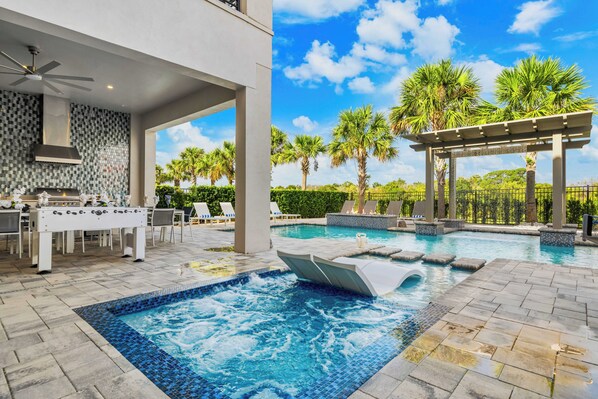 A pool area with a hot tub, lounge chairs, and a covered seating area.