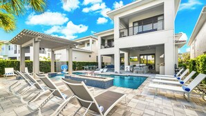 A modern outdoor pool area with lounge chairs, a fire feature, and a covered seating area.