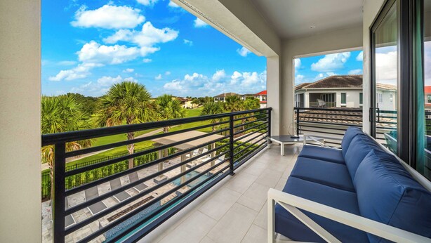 A balcony with a view of a green landscape and a clear sky.