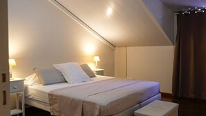 Ein Schlafzimmer mit Bett, Nachttischen, einer Bank und einer Deckenleuchte.