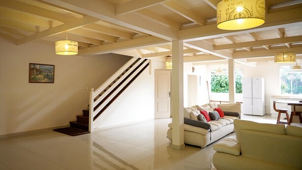 Ein geräumiger Wohnbereich mit Treppe, einem weißen Sofa und einem Essbereich mit Tisch und Stühlen.