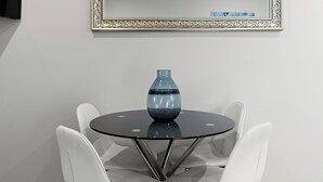 A round glass table with a blue vase, surrounded by white chairs, under a decorative mirror. - Prickly Pear Stays in Mayfield West (Mayfield West)
