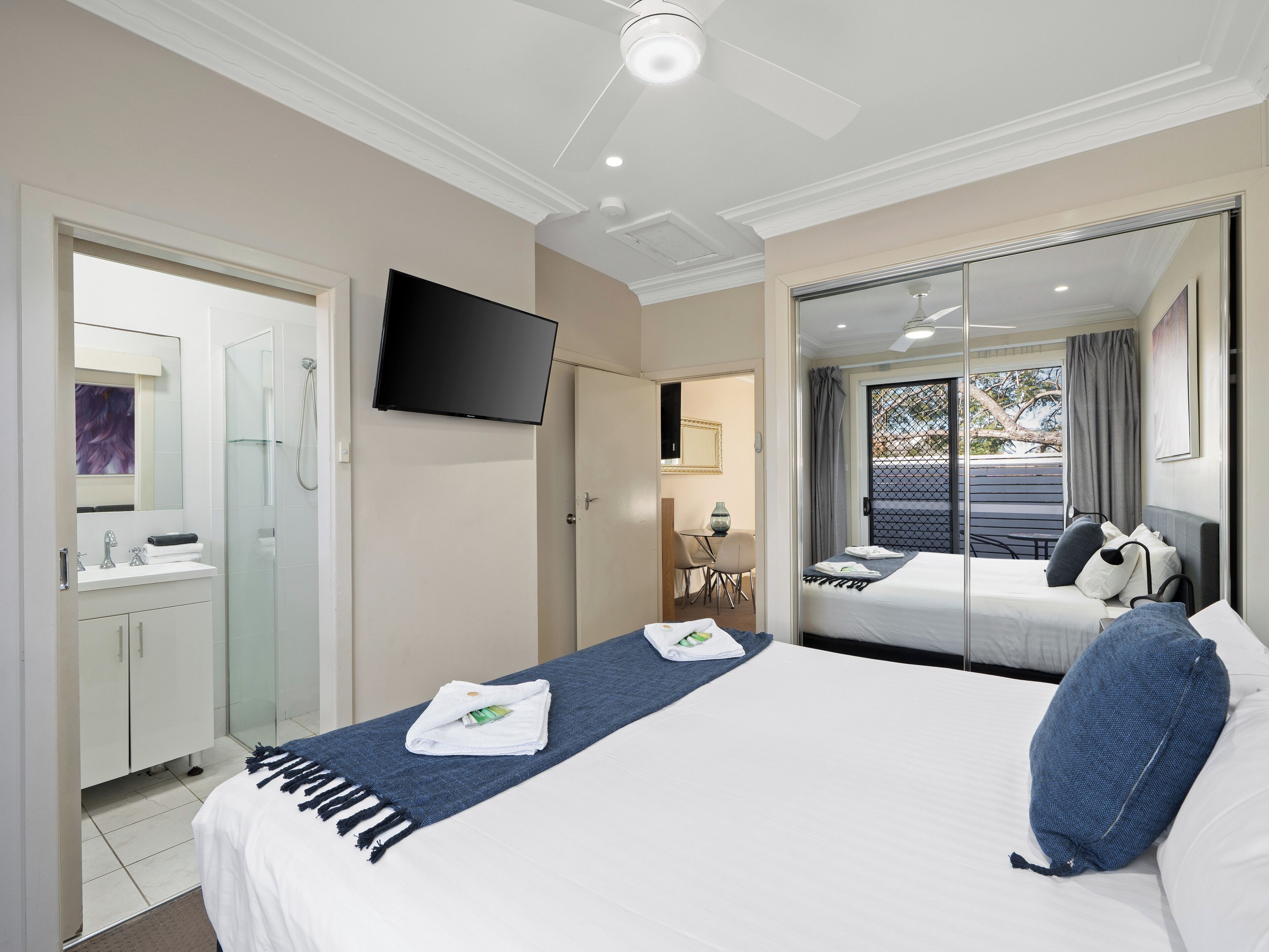 A hotel room with a bed, a TV, a bathroom, and a balcony with a view.