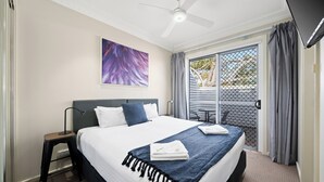 A hotel room with a bed, a ceiling fan, a window with curtains, and a painting on the wall. - Prickly Pear Stays in Mayfield West (Mayfield West)