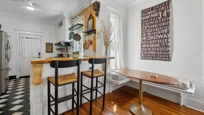 Eine Küche mit einer Holztischinsel, zwei Barhocker, einem runden Tisch und einer Wand mit einer Liste von Straßennamen.