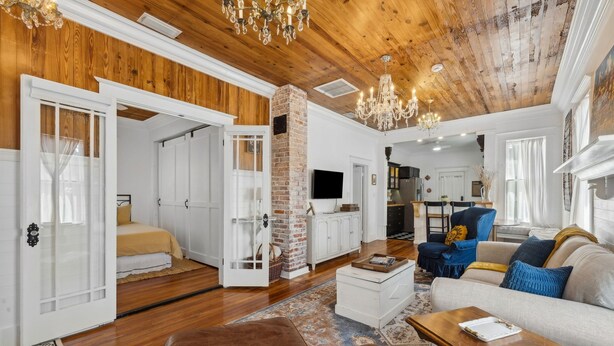 Ein geräumiges Wohnzimmer mit Holzboden, einem Kamin aus Ziegeln und einer Kristallleuchter.