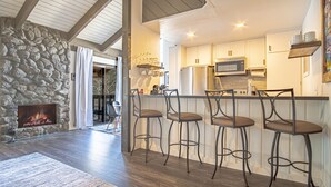 Een moderne keuken met een stenen muur, houten vloer en een bar met krukken.
