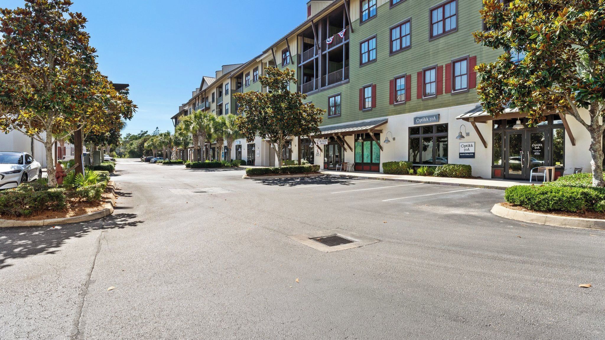 A street with multi-story buildings, a clear sky, and a parking lot.