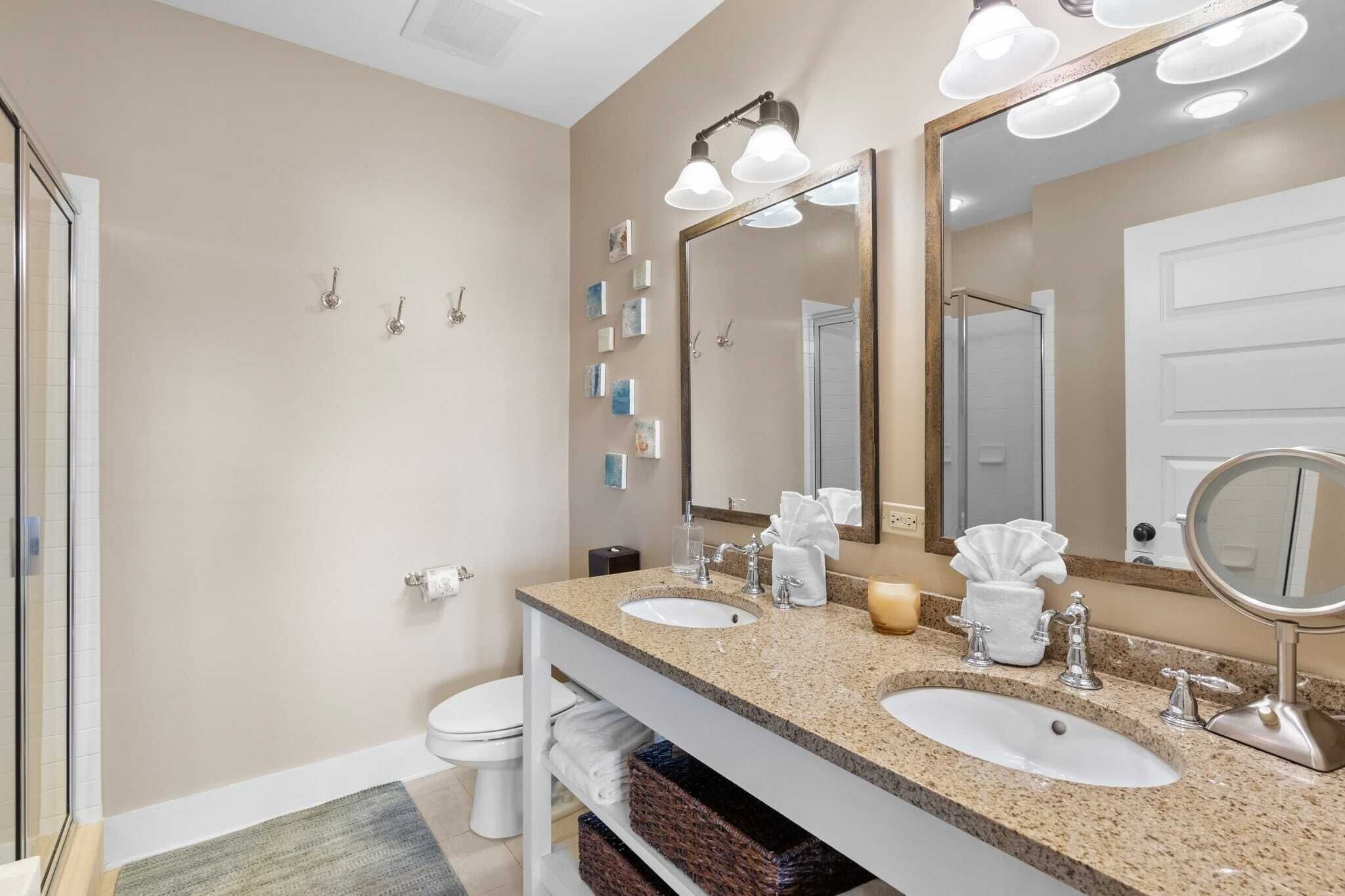 A modern bathroom with two sinks, a large mirror, and a shower.