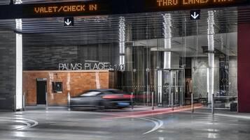 Ein moderner Gebäudeeingang mit einer digitalen Anzeige, die Valet-Service/Check-in und eine Durchfahrt für Taxis kennzeichnet.