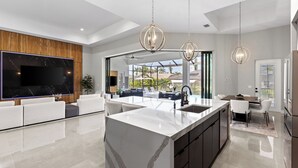 A modern kitchen with a large island, built-in appliances, and pendant lighting.