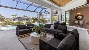 A modern lounge area with a pool view, a large sofa, and a coffee table.