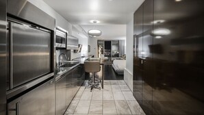 Een moderne keuken met roestvrijstalen apparatuur, een centraal eiland en uitzicht op een stadsbeeld 's nachts.