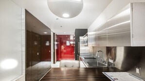 Een moderne keuken met roestvrijstalen apparatuur, een houten aanrecht en een rode accentmuur.