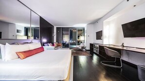 Une chambre d’hôtel moderne avec un grand lit, un bureau et une télévision.