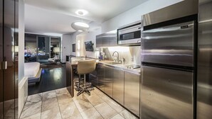 Une cuisine moderne dotée d’appareils électroménagers en acier inoxydable, d’un coin bar et offrant une vue sur la ville grâce à de grandes fenêtres.